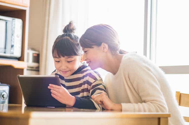 Madre e hija jugando con una tableta digital en habitación