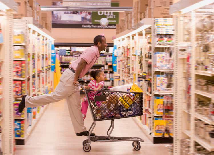 African father pushing daughter in grocery cart