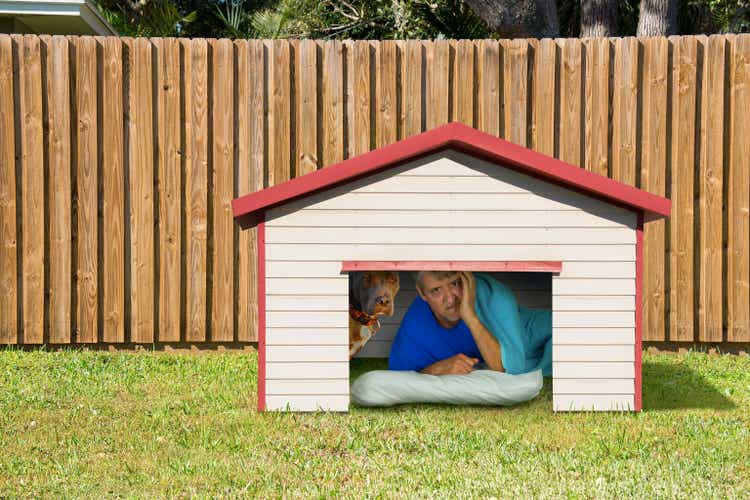 Husband or boyfriend man sleeping in the doghouse because of domestic problems