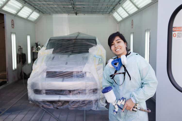 Hispanic worker preparing to paint car in auto body shop