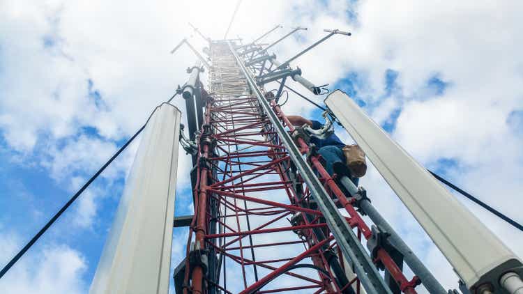 Worker climbing on high cellular network tower