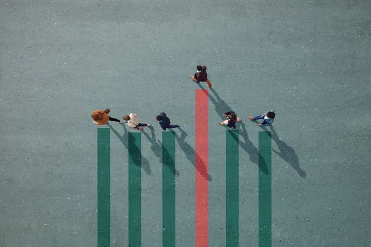 Business people walking in a line on a bar chart drawn on the asphalt, one person walking away.