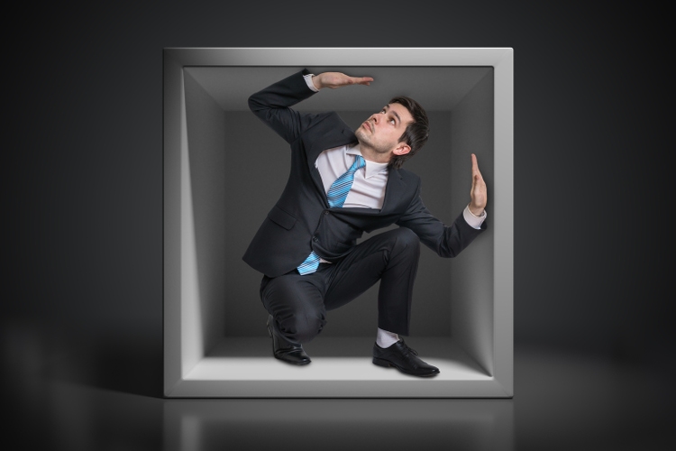 Young businessman trapped inside uncomfortable small box.
