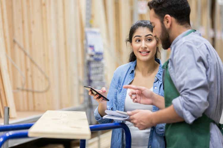 Female home improvement store customer talks with employee