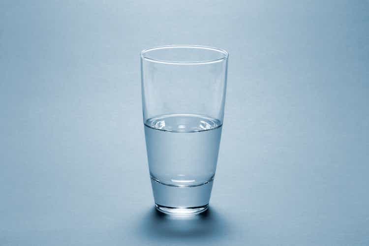 Half full water glass over blue background