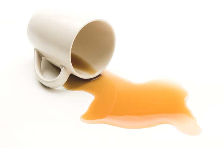 Mug knocked over with spilt coffee on white background