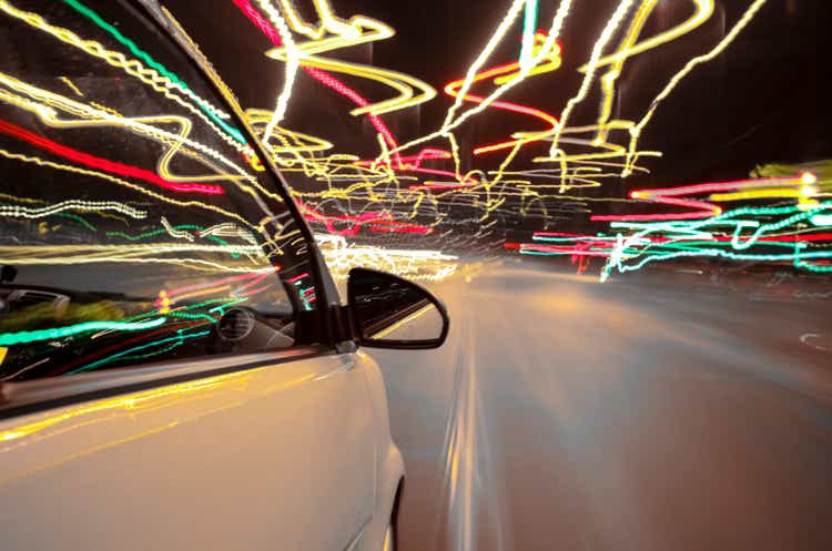 car drives through Berlin while night - right side of the car with wing-mirror in foreground - long exposure