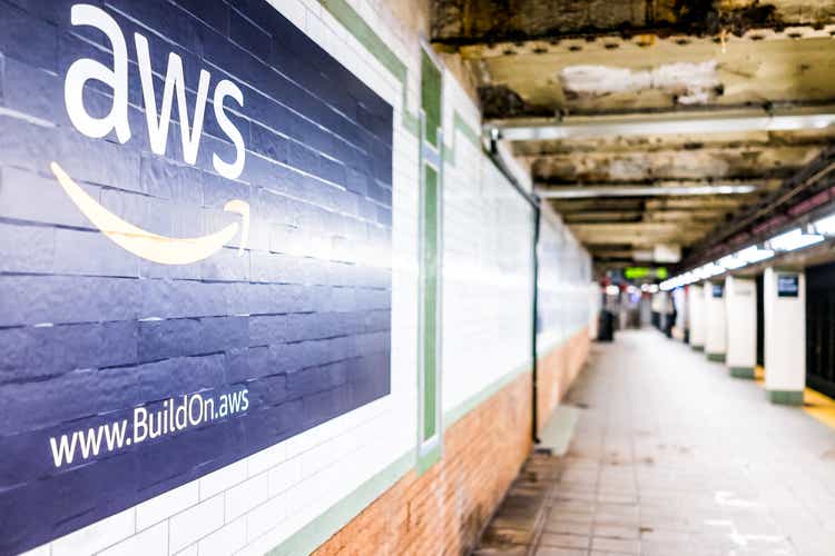 Closeup of Amazon Web Services AWS advertising sign in subway station in NYC, tiled wall, arrows, side