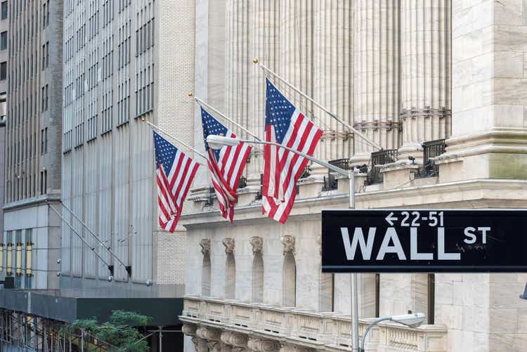 Wall Street sign in New York City with the New York Stock Exchange background.