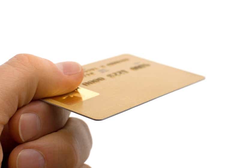 Closeup of a Consumers Hand Holding Gold Credit Card Isolated