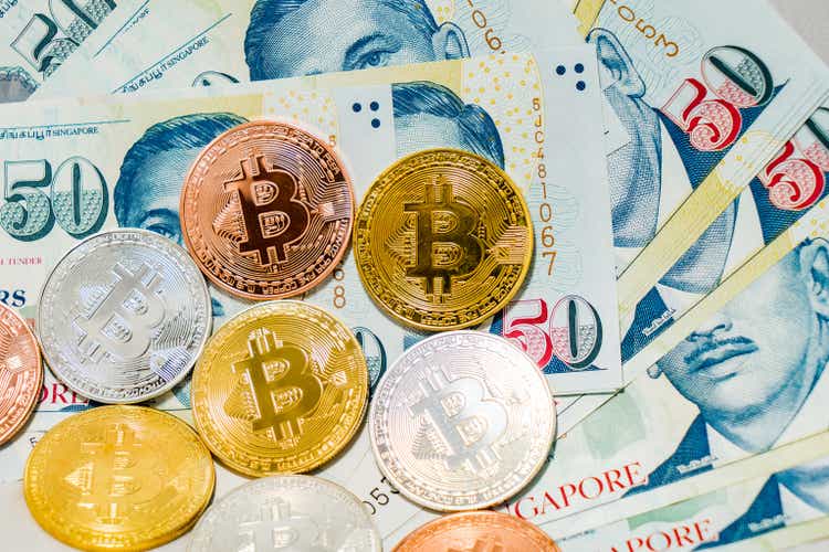 Singapore Dollar banknotes and Bitcoin Cryptocurrency coins on White background