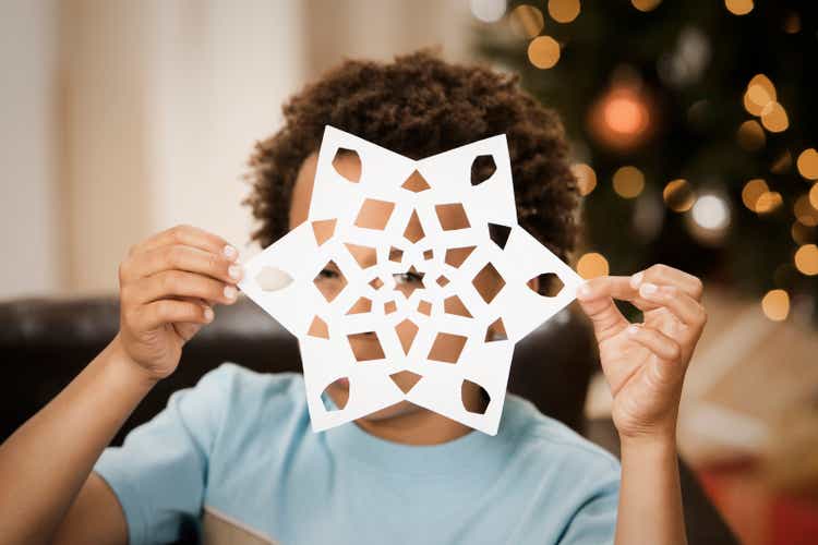 Mixed race boy holding paper snowflake