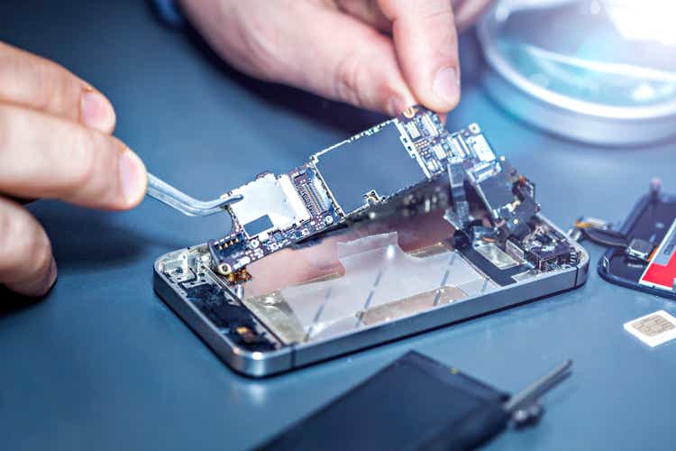 Serviceman is repairing a damaged mobile phone.