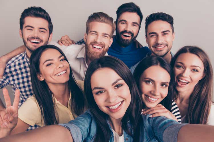 Cheers! Funky mood. Close up of an eight excited friend`s selfie, taken by brunette girl. Young people enjoy their company, smile, have fun