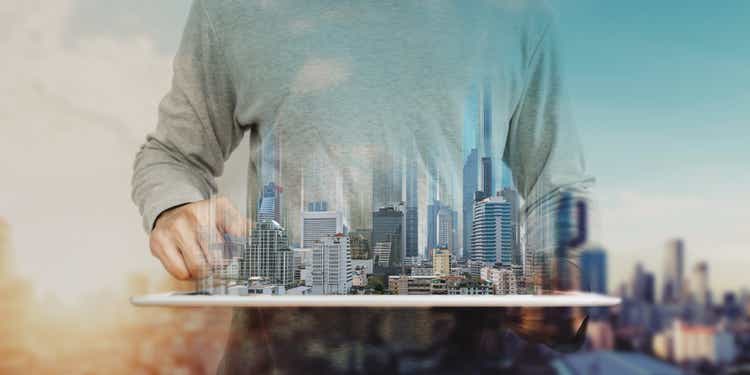 a man working on digital tablet, with Hologram futuristic modern buildings. City sunrise background