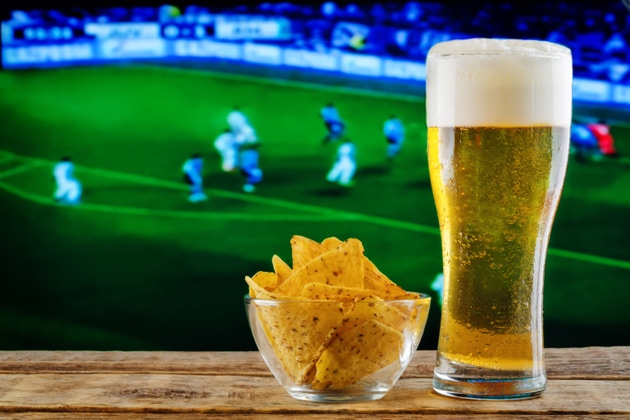 Pahar de bere și gustare pe fundalul unui televizor de fotbal