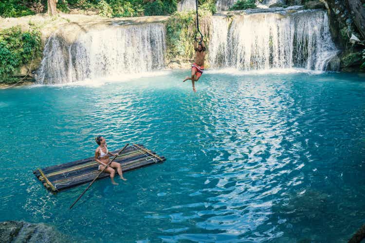 Young couple playing at beautiful waterfall in the Philippines