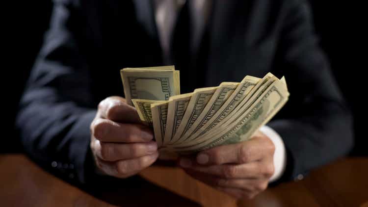 Corrupt official holding bundle of money, taking bribe for abuse of power
