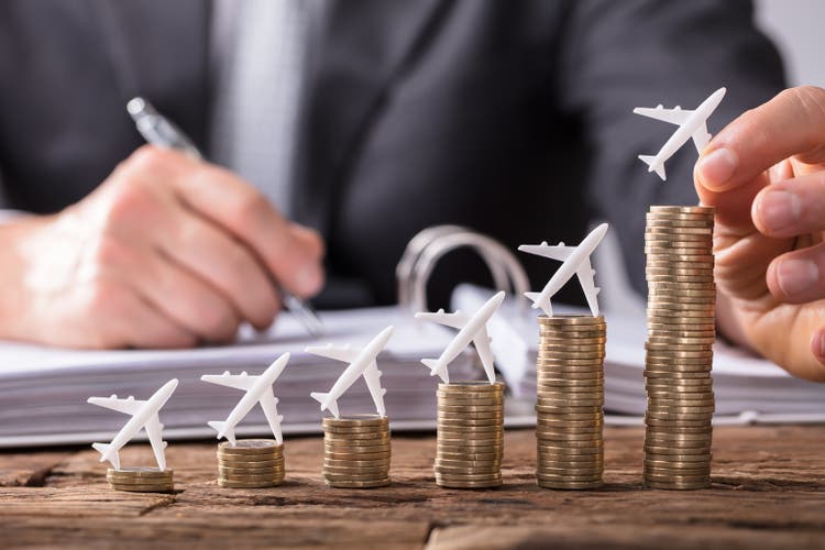 Human Hand Placing Small Aeroplane On Increasing Stacked Coins