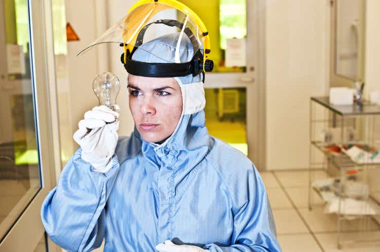 Quality Control Female Engineer Examines A LED Lamp in Laboratory / Cleanroom