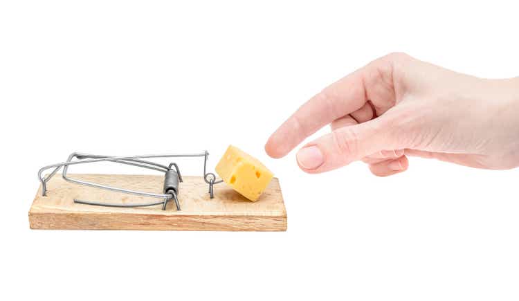 Woman"s hand taking cheese from mousetrap on white background. Free cheese only in mousetrap.