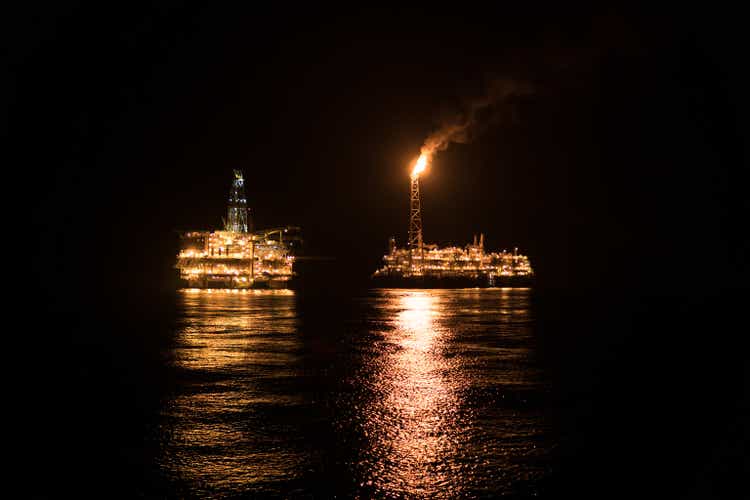 FPSO tanker vessel near Oil Rig at night. Offshore oil and gas industry