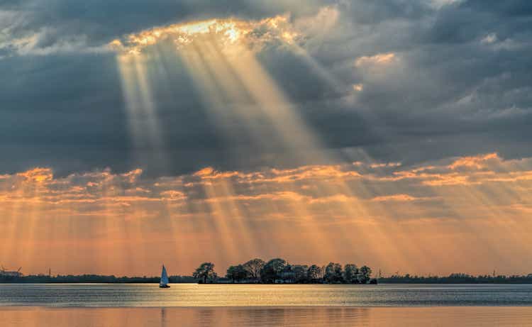 Sunbeams through cloudscape on lake.