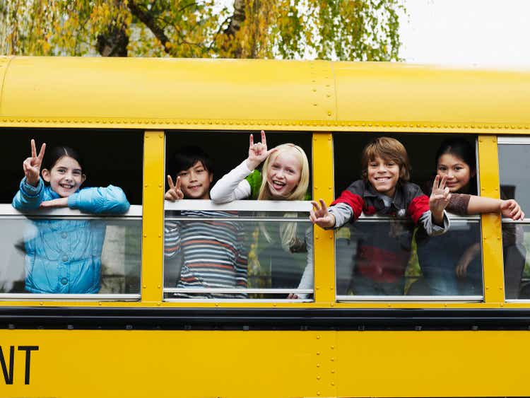Group of young students hanging out bus windows