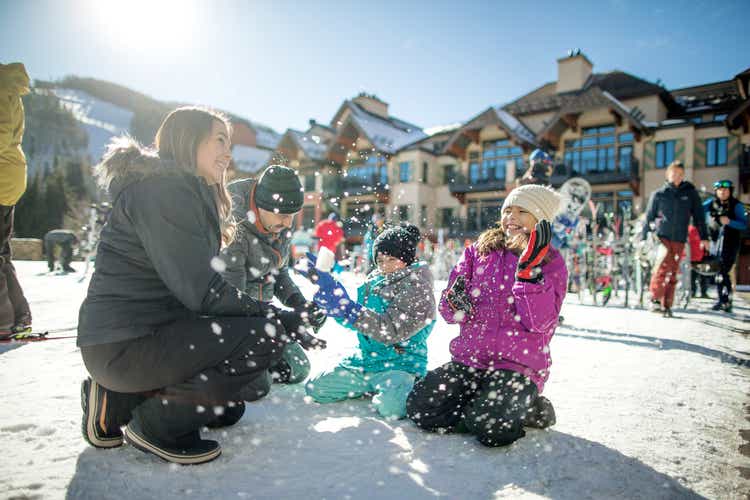 Hispanic family throwing snow and having fun on a nice sunny day at a ski resort.