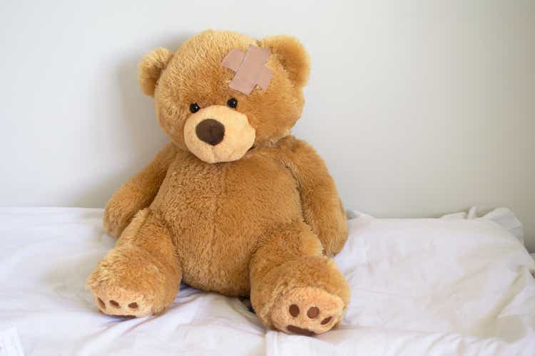 Sad teddy bear sit on the white bed