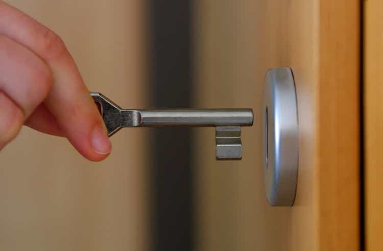 Close-up of fingers inserting a key into a door lock