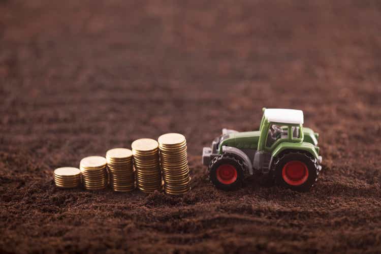 Tractor miniature with coins on fertile soil land