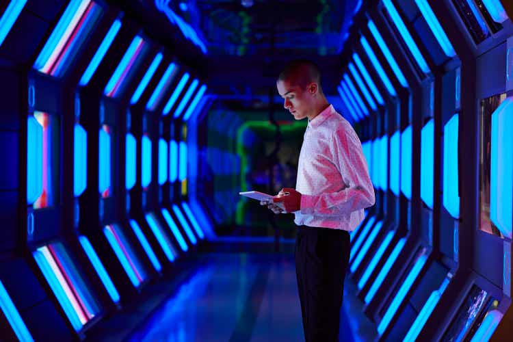 Young businessman looking at digital tablet in spaceship like corridor