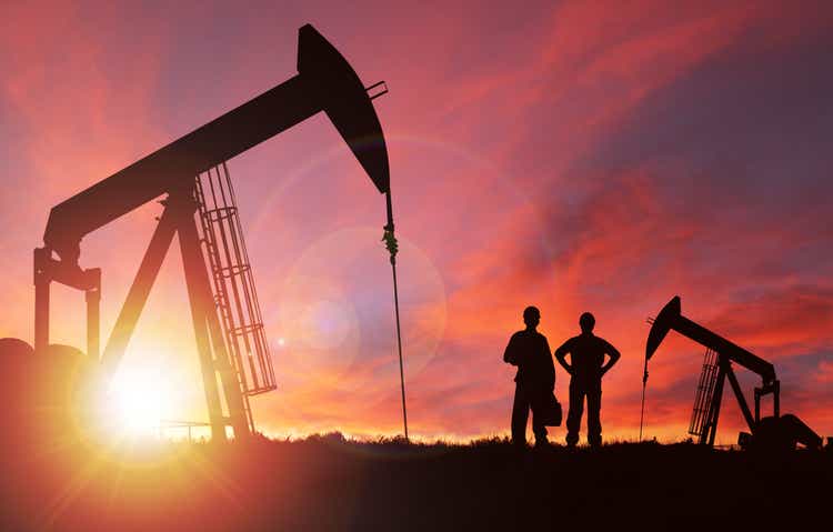 Puesta de sol sobre Pumpjack silueta con copia espacio