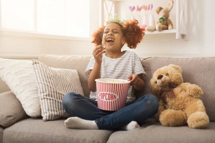Laughing black little girl watching movie at home