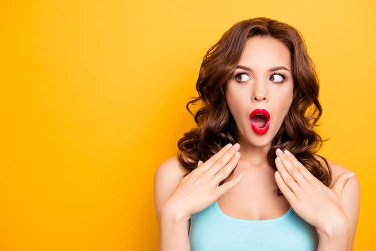 Portrait with copy space for advertisement of shocked afraid woman looking with eyes at empty place having wide open mouth eyes gesturing palms isolated on yellow background