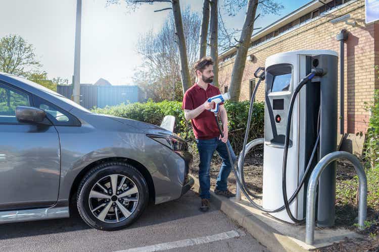 Driving instructor charging electric car at car park charging point