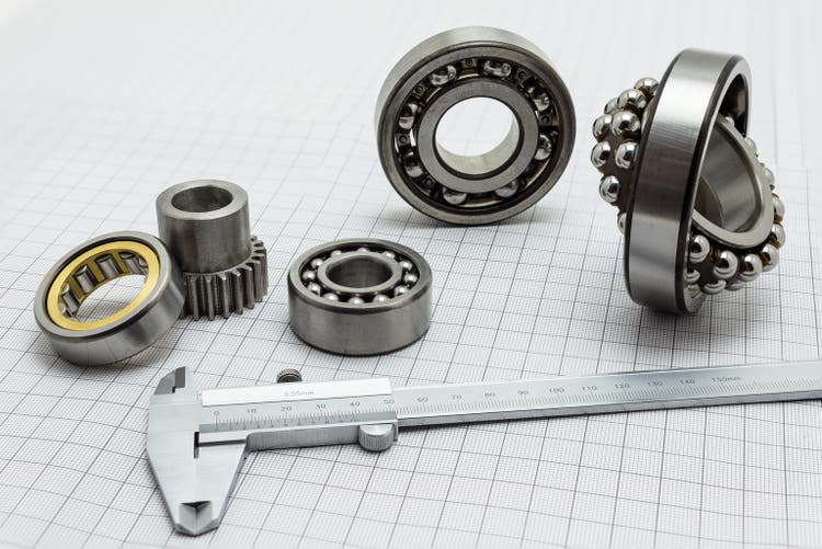 Vernier caliper lying on drafting paper with bearing and small gear.