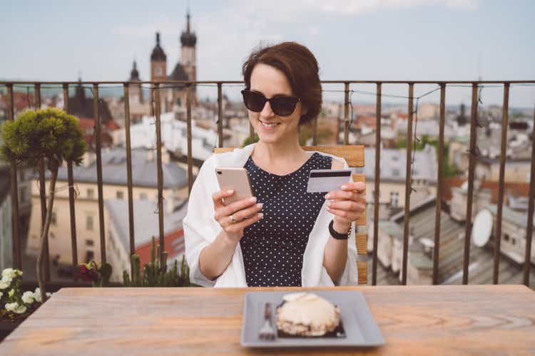 Lachende vrouw reizen in Europa en online winkelen met credit card