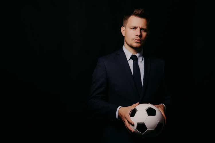 young handsome businessman holding a football on black background studio