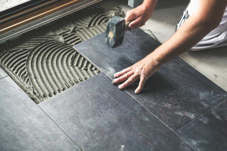Worker placing ceramic floor tiles