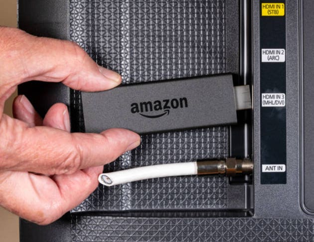 Senior man hand inserting Amazon Fire TV device