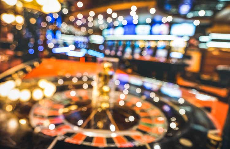 Fondo desenfocado borroso de la ruleta en el salón del casino - Concepto de juego con sala de juegos desenfocada con máquinas tragamonedas de video póquer y luces borrosas multicolores