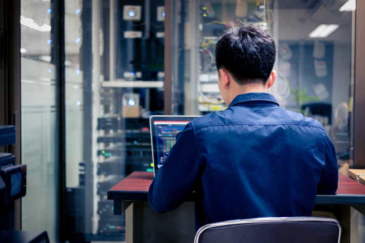 Technici, die laptop gebruiken bij het analyseren van de server in de serverruimte