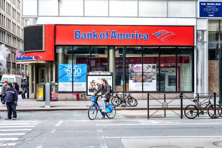 Street view on Bank of America branch in NYC with people waiting, pedestrians crossing, crosswalk, bike, road in Manhattan