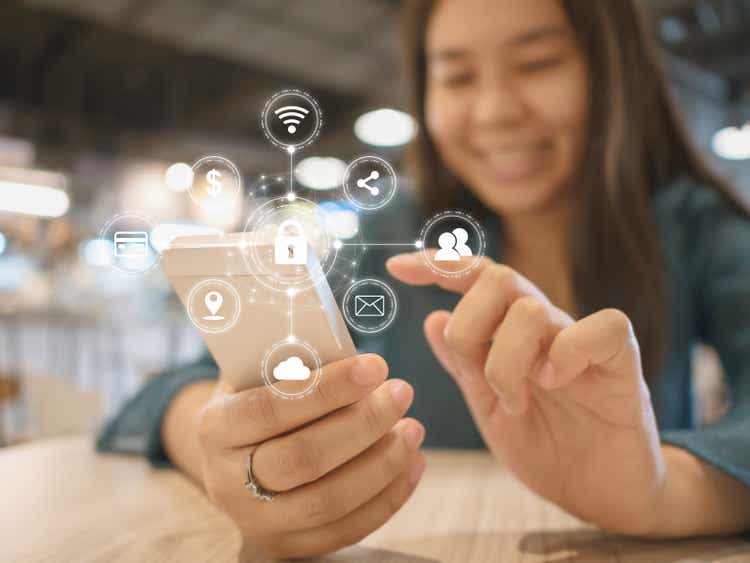 Young woman smiling and using smartphone and with icon graphic symbol cyber security network protection of connection devices and secure personal data in mobile phones
