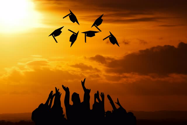 Silhouette of a group of people with graduation caps thrown in the air