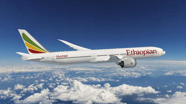 This image shows a Boeing 777-9 airplane in Ethiopian Airlines colors with clouds in the background.