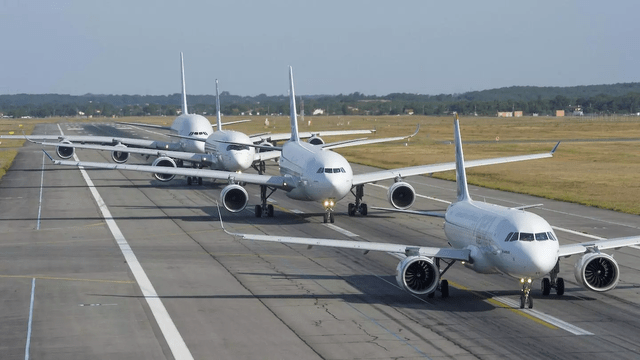 This image shows a line up of Airbus commercial airplanes on a runway.