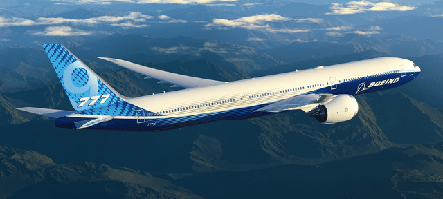 This image shows a Boeing 777-9 airplane in the skies with mountains in the background.